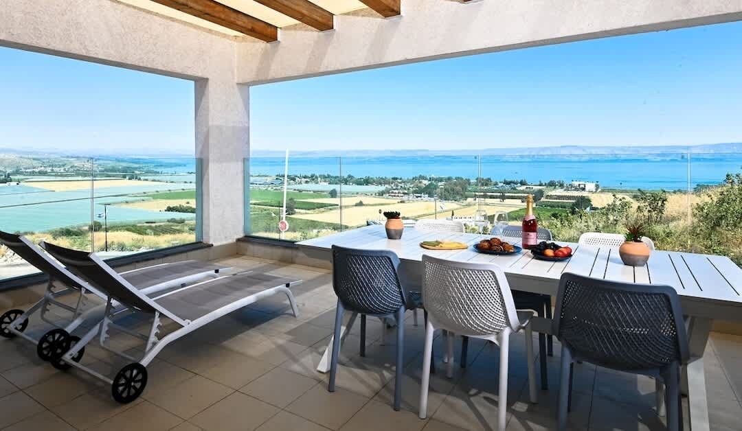 Una terraza con mesa lista para comer, una silla de lounge y vistas al paisaje.