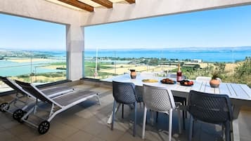 Una terraza con mesa lista para comer, una silla de lounge y vistas al paisaje.