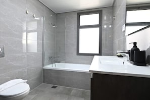 Un baño moderno con ducha de vidrio, inodoro blanco y tocador con espejo.