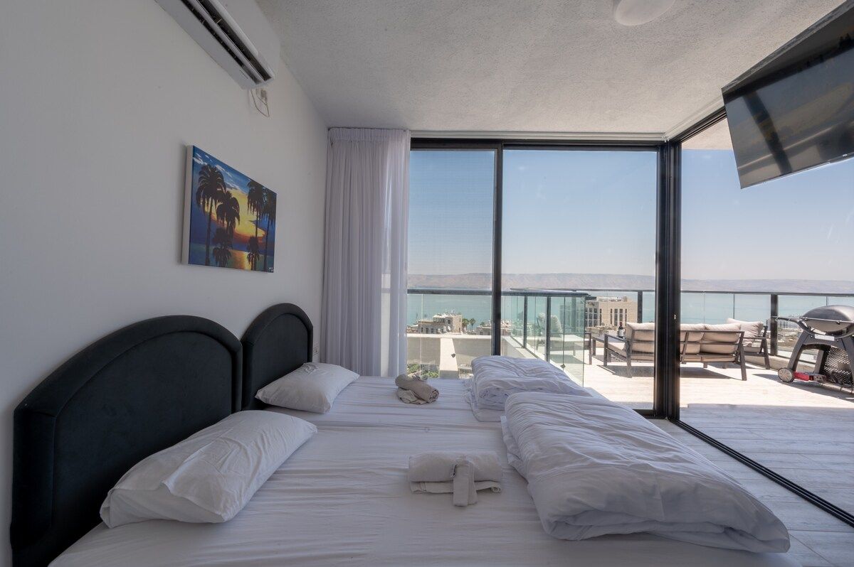Une chambre d’hôtel avec un lit, un tableau et un balcon offrant une vue.