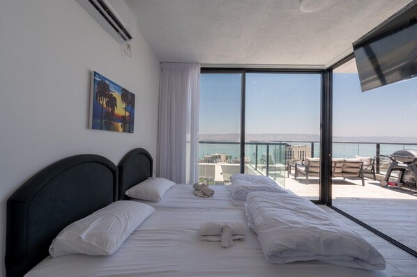 Ein Hotelzimmer mit Bett, einem Gemälde und einem Balkon mit Blick.
