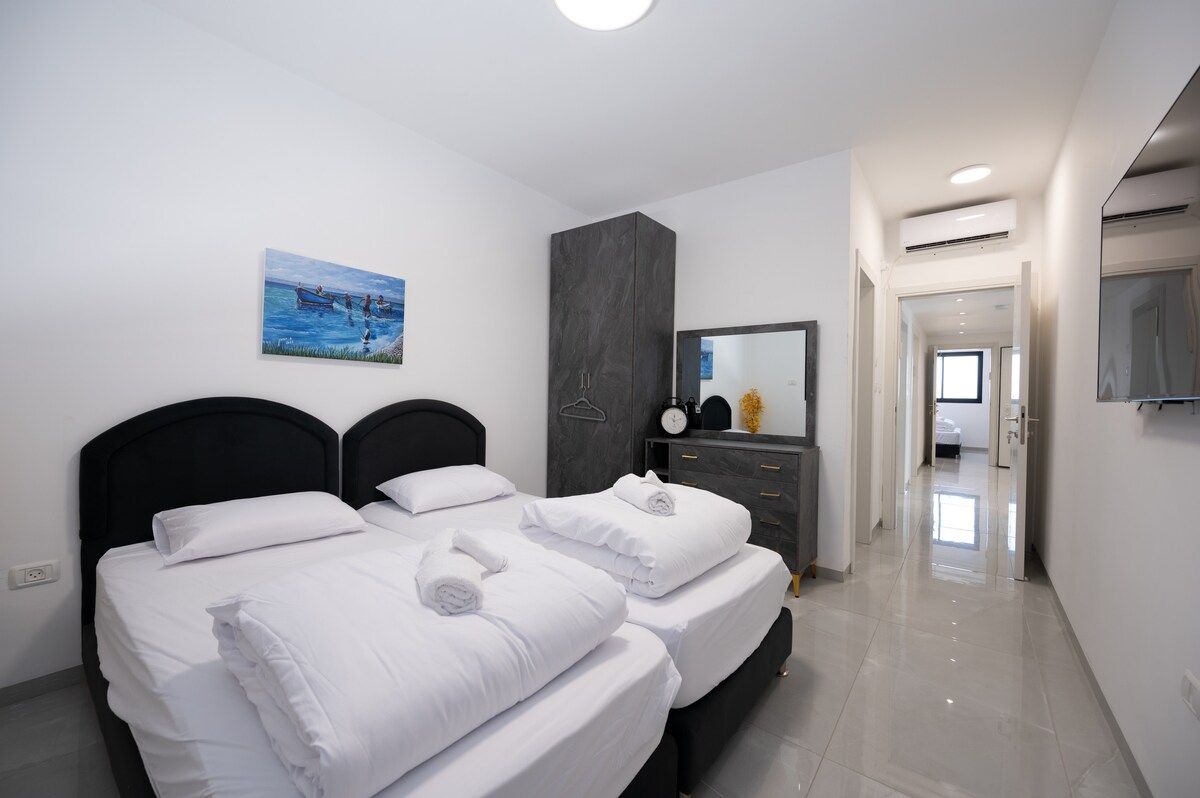 Une chambre d’hôtel avec deux lits, un grand miroir, un tableau au mur et un design moderne.
