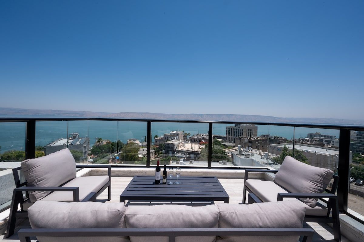 Un balcon avec un canapé et une table, offrant une vue sur le paysage urbain et la mer.