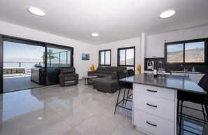 Ein moderner Wohnraum mit Küche, Sitzecke und großen Fenstern mit Blick ins Freie.