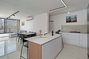 Een moderne keuken met een centraal eiland, een eethoek met stoelen en een groot raam met uitzicht op de stad.