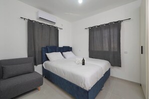 Een slaapkamer met een bed, een stoel en een airconditioner.