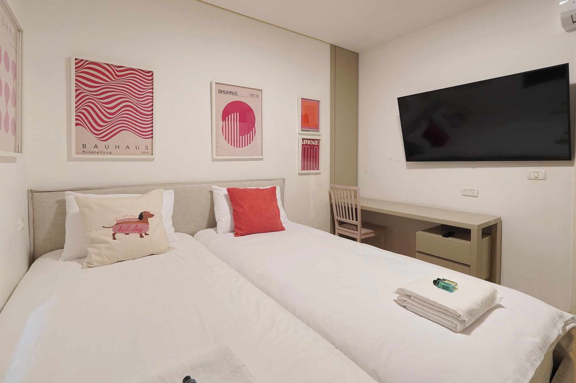 A hotel room with a bed, a desk, and a TV.