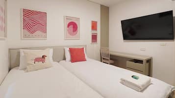 A hotel room with a bed, a desk, and a TV.