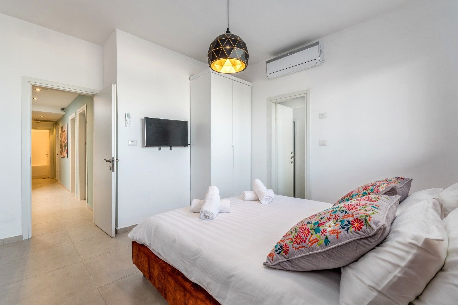 Une chambre d’hôtel avec un lit, une télévision, une douche et un couloir.