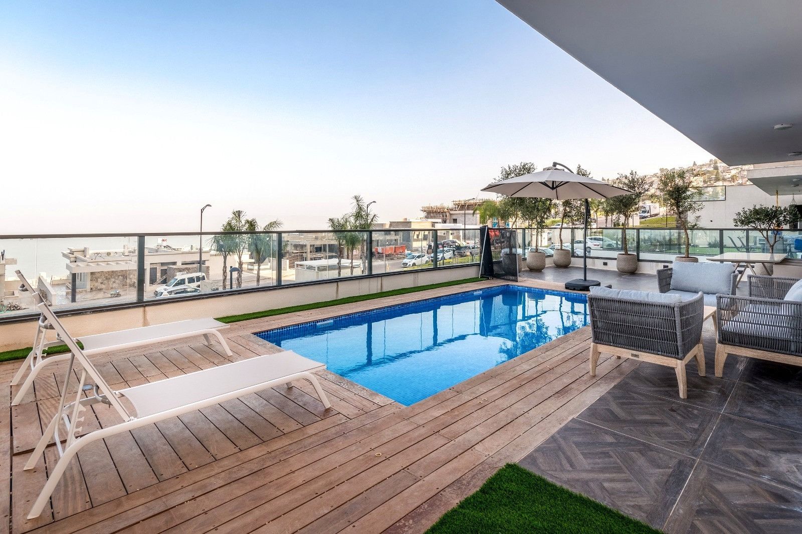 Un espace piscine sur le toit, offrant une vue sur la ville, avec une terrasse en bois et du mobilier d’extérieur.