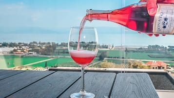 Una botella de vino Donato siendo servido en una copa sobre una mesa de madera, con una vista panorámica de fondo.