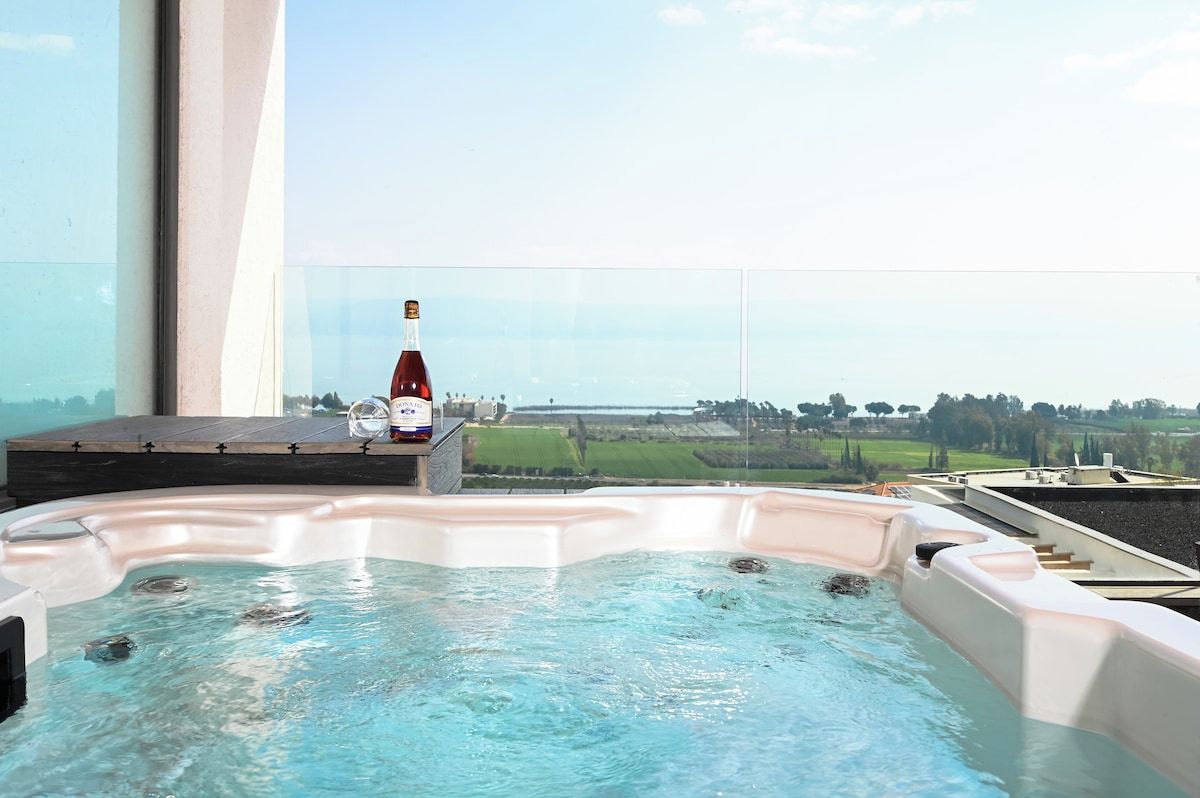 Un bain à remous avec une bouteille de vin sur un balcon donnant sur un paysage.