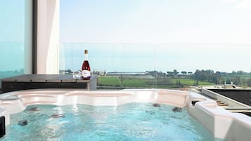 Un jacuzzi con una botella de vino en un balcón con vistas al paisaje.
