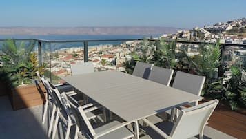 A terrace with a table and chairs, overlooking a coastal town.