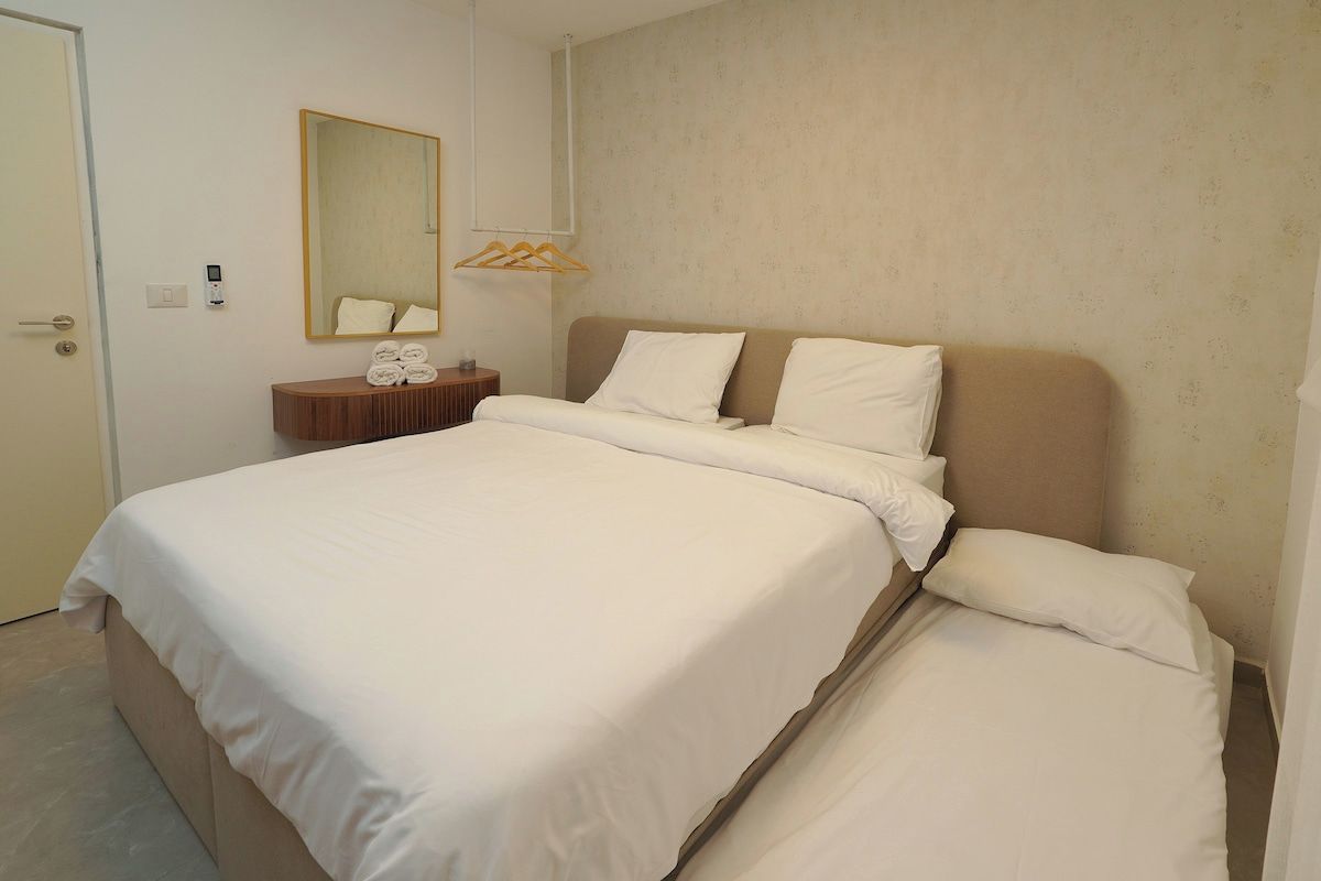 A hotel room with a large bed, a bedside table with a mirror, and a wall-mounted towel rack.