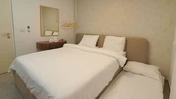 A hotel room with a large bed, a bedside table with a mirror, and a wall-mounted towel rack.