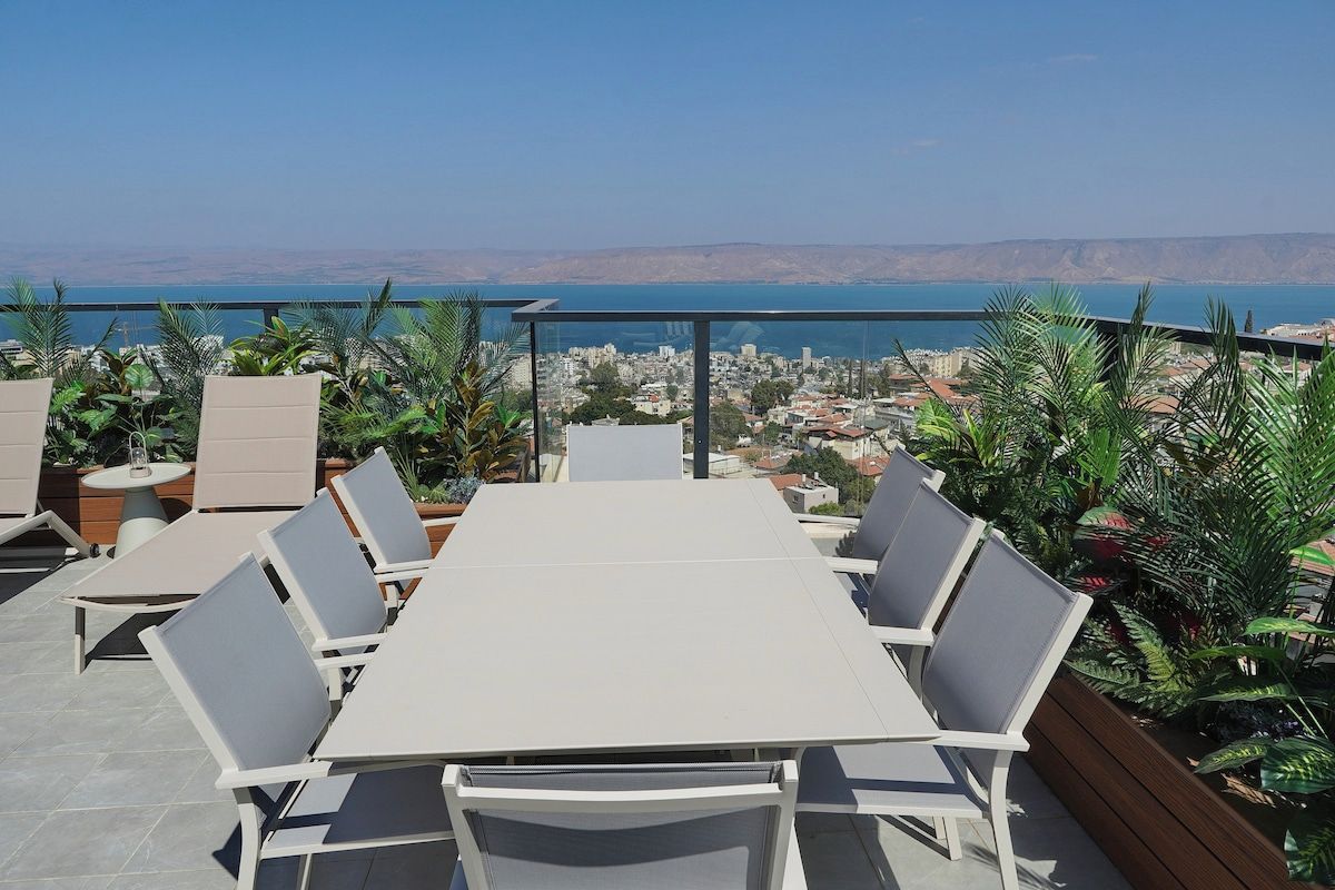 A terrace with a table and chairs, overlooking a cityscape and the sea.