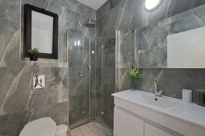 Une salle de bain moderne avec une douche à parois de verre, un lavabo blanc et un miroir au-dessus du lavabo.
