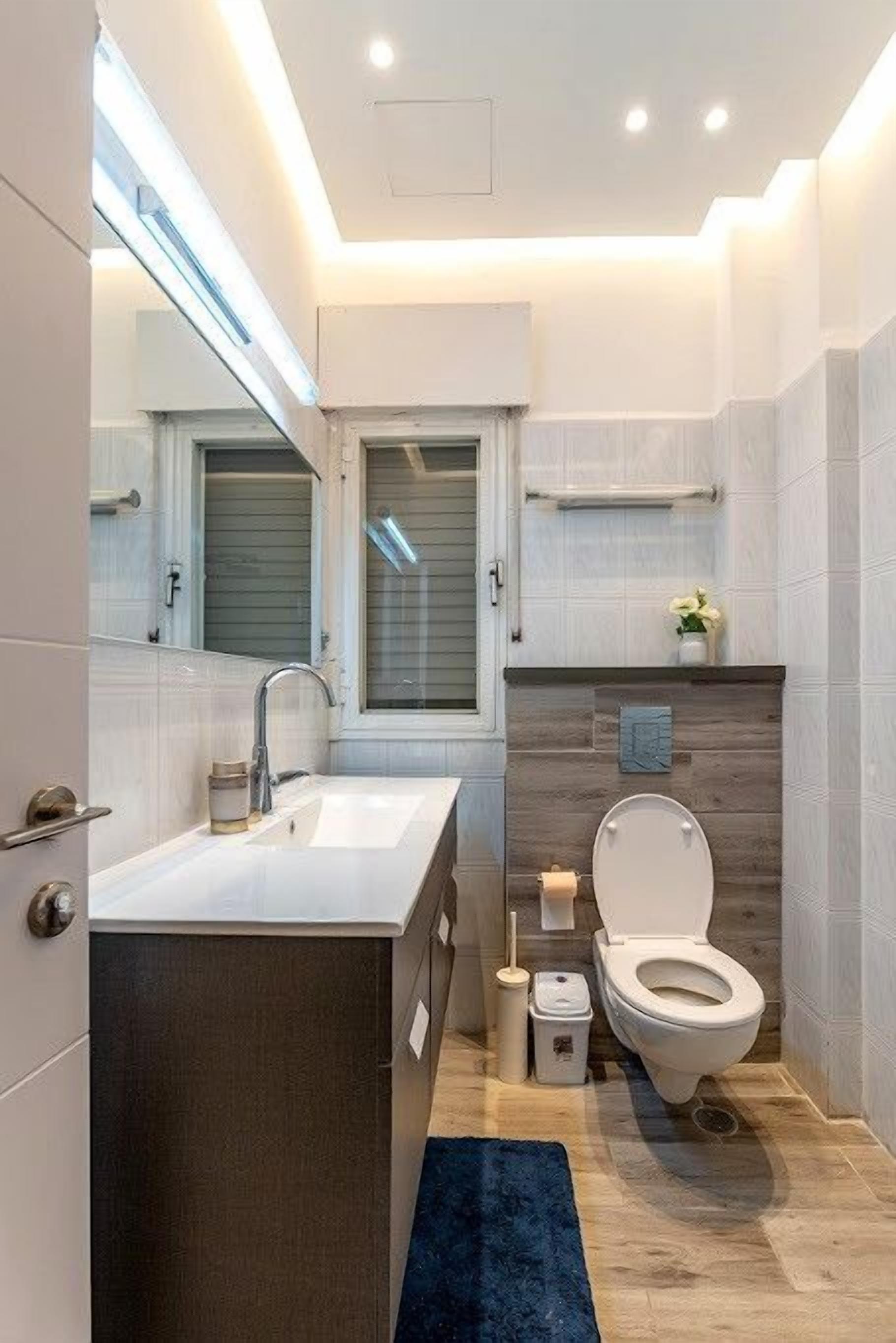 Une salle de bain moderne avec un grand miroir, un lavabo et des toilettes.