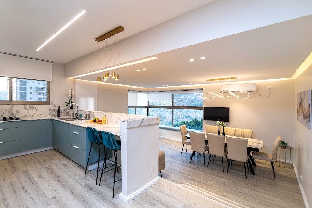 Une cuisine moderne dotée d’un îlot central, de tabourets de bar et d’un coin repas avec une table et des chaises.
