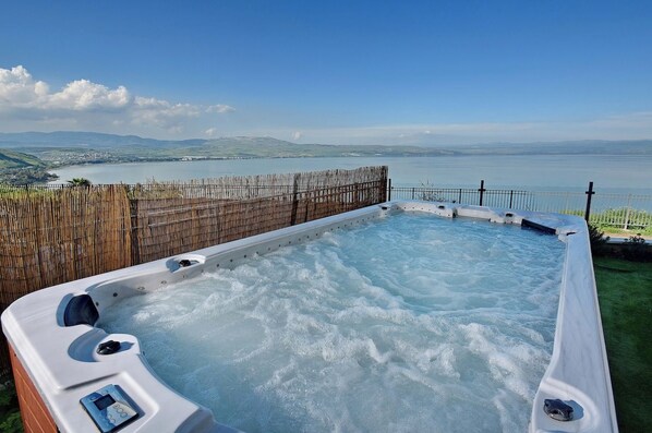 Een hottub met uitzicht op een meer en heuvels.