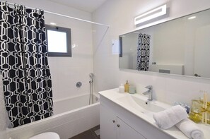 Een moderne badkamer met een douche, een wastafel met spiegel en toiletartikelen.