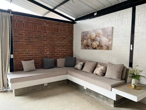 Una sala moderna con un sofá modular, una pared de ladrillo y un cuadro grande con motivos florales.