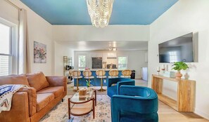 Un salon avec un canapé, des fauteuils, une table basse et un téléviseur.