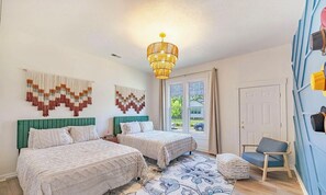 Une chambre avec deux lits, un lustre, un tapis à motifs et une vue par la fenêtre.