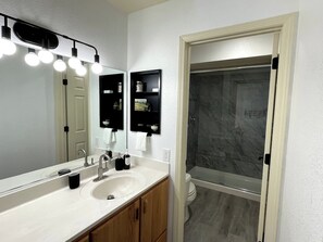 Un bagno con un lavandino bianco, uno specchio e una cabina doccia.