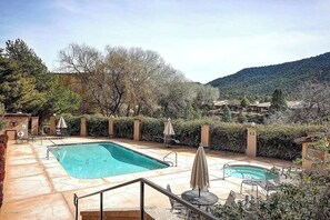 Area piscina con due vasche, circondata da alberi e colline.