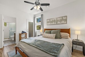 A bedroom with a bed, a ceiling fan, a window with curtains, a bedside table with a lamp, and a painting on the wall. - Central 2BD/2.5Bth - Fire pit , Fast Wifi, Sleeps 5 (Flagstaff)