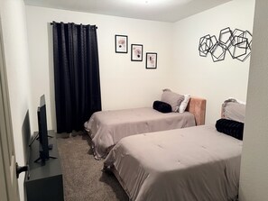 A room with two beds, a TV, and artwork on the walls. - 3-bedroom house with relaxing character in a small quiet neighborhood. (Orange)