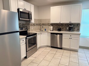 A modern kitchen with stainless steel appliances, white cabinetry, and a tiled backsplash. - 3-bedroom house with relaxing character in a small quiet neighborhood. (Orange)