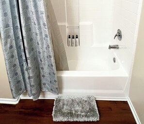 A bathroom with a bathtub, a shower curtain, and a small rug. - Amazing Apt/nice pool/gym/free parking (Culver City)