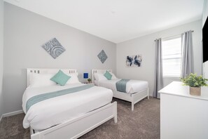 Habitación de hotel con dos camas, un escritorio y una ventana con cortinas.