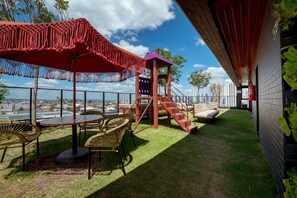 Un patio exterior con una mesa, sillas y una zona de juegos para niños con un tobogán.
