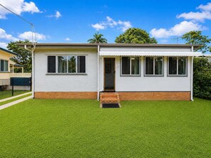A single-story house with a flat roof, a front door, and a small porch. - Arty Beach Shack Deception Bay | Pets + Parking (Deception Bay)