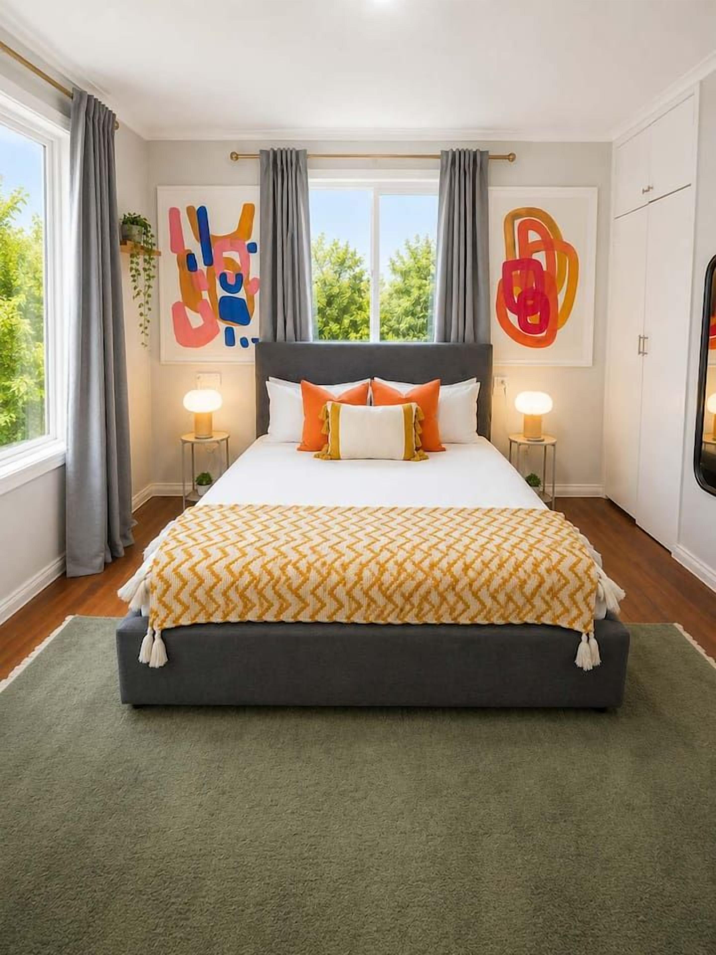 A bedroom with a large bed, two bedside tables, and a view of greenery outside.