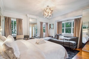 Hotellihuone, jossa on suuri sänky, sohva, työpöytä ja kattokruunu.