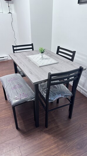 A dining table with four chairs, a potted plant, and a patterned table runner. - Creekside Haven Suite (Moncton)