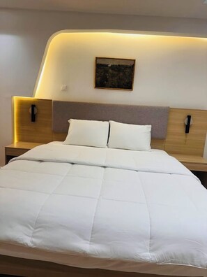 Une chambre moderne avec un grand lit, deux tables de chevet et une œuvre d’art accrochée au mur.