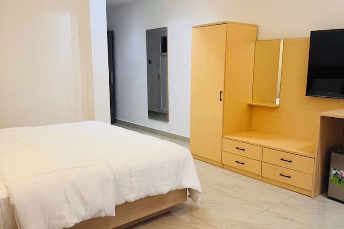 Une chambre d’hôtel avec un lit, une armoire, une télévision et une chaise.