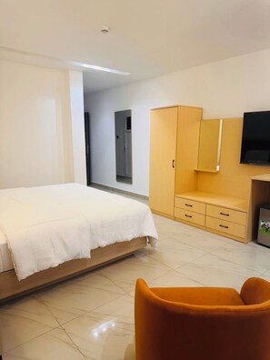 Une chambre d’hôtel avec un lit, une armoire, une télévision et une chaise.