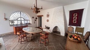 Un comedor con una mesa redonda y sillas, una chimenea y un suelo de piedra.