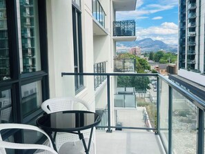 A balcony with a glass railing, a table, and two chairs. - DOWNTOWN LAKEVIEW LUXE 2BD apartment in marvelous Kelowna with AC and comfort (Kelowna)