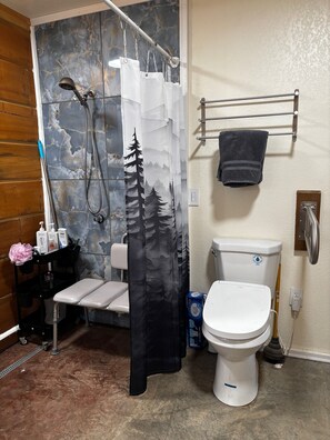 Kylpyhuone, jossa on suihku, wc ja penkki.