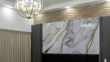 A modern bedroom with a large bed, a chandelier, and a marble-patterned wall.