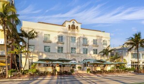 A hotel with a central courtyard, outdoor seating area with umbrellas, and palm trees. - Marriott Vacation Club Studio 1 bathroom Miami Beach (Miami Beach)