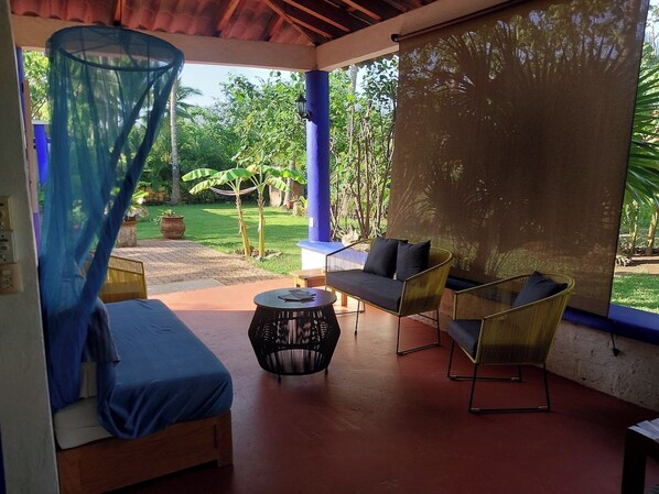 A covered outdoor seating area with a sofa, chairs, and a round table. - Private Room Steps to Beach Tropical Garden Retreat Breakfast Included (Punta Perula)